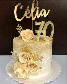 a white cake with gold flowers and the word celia on top is sitting on a table