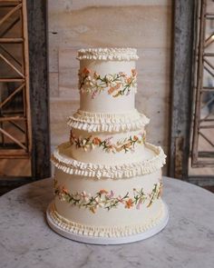 a three tiered wedding cake with flowers on the side and ruffles at the bottom