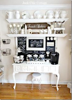 a white table topped with lots of cups and saucers next to a wall mounted chalkboard