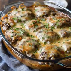 a casserole dish with meat and cheese in it on a blue cloth next to a fork