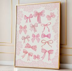 pink bows are displayed on a white wall in front of a gold framed art print