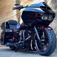 a black motorcycle parked in front of a stone wall