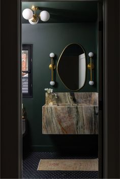 a bathroom with green walls, marble sink and gold faucet light fixture on the wall