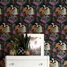 a white dresser sitting in front of a wallpaper covered with animals and palm trees