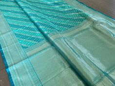 Gorgeous banarasi saree in blue. Small patterns and lines woven with silver silk thread all over alternate sky blue and teal base gives the saree a unique look. Comes with a sky blue blouse piece with motifs and saree border (shown in 3rd and 10th pic). Suitable to wear in a formal occasion or festival. Saree is 5.5+ yards long and 44 inches wide Blouse piece is 33 inches Care: Dry clean only. Disclaimer: Color and shade of saree may vary in the pictures than the actual item. There might be slight weaving irregularities since the product is woven by hand. Traditional Light Blue Handloom Saree, Light Blue Dupatta With Zari Weaving For Diwali, Light Blue Saree With Zari Weaving In Traditional Drape, Light Blue Saree With Zari Weaving, Festive Light Blue Saree With Zari Weaving, Festive Light Blue Handloom Saree, Blue Saree With Weaving Work For Wedding, Blue Wedding Dupatta With Weaving Work, Blue Traditional Wear With Weaving Work For Diwali