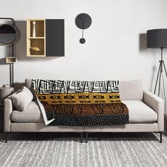 a living room with a couch, lamp and clock on the wall next to it