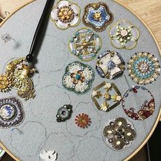 a clock made out of different types of brooches on a wooden table top