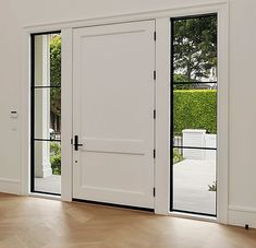 an empty room with white doors and wood flooring on the side, looking out onto a garden