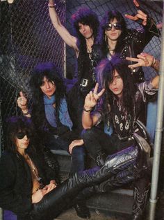 the band kiss posing for a photo in front of a chain link fence with their hands up