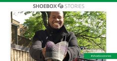 a man holding a stuffed animal in front of a fence with the words shoebox stories on it