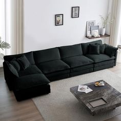 a black couch sitting on top of a white rug in a living room next to a window