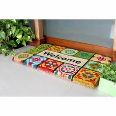 a welcome mat is on the floor next to a potted plant and doormat