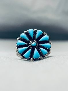 "MAKE US AN OFFER BY CLICKING THE \"MESSAGE SELLER\" Button- Here we have an impressive vintage Zuni ring featuring a handcarved silver flower with Sleeping Beauty turquoise stones, silver rope, and silver beads, all on a double rail silver band that graduates to a solid silver band! Truly Charming! The largest stone measures around 1/4\" x 1/8\". The ring face measures around 3/4\" x 3/4\". The ring size is around 6. Sterling silver, marked. Sturdy 3 grams. Make Us an Offer- Due to the high dem Collectible Round Turquoise Ring, Adjustable Blue Turquoise Ring Collectible, Antique Blue Turquoise Ring For Anniversary, Southwestern Style Blue Round Ring, Antique Turquoise Anniversary Ring, Vintage Turquoise Ring For Wedding, Vintage Oval Turquoise Ring For Wedding, Antique Blue Cluster Ring, Vintage Oval Turquoise Wedding Ring