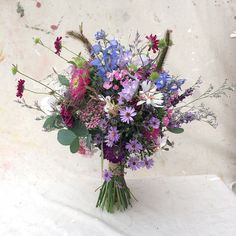 a bouquet of wildflowers and other flowers on a white tableclothed surface