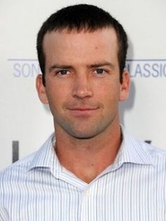 a man in a striped shirt is posing for a photo on the red carpet at an event