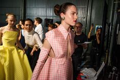 a woman in a pink and white checkered dress walks down the runway with other people behind her