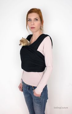 a woman is wearing a black wrap around her shoulder and holding a cat in her lap