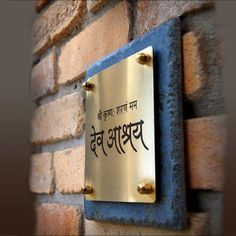 a metal plaque mounted to the side of a brick wall with writing in english and chinese