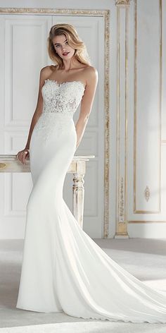 a woman in a white wedding dress standing next to a table