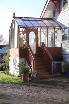 a house with a glass roof and stairs leading up to the front door, on a sunny day