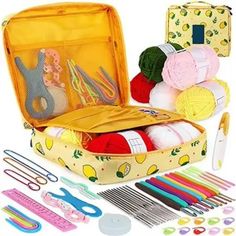 an open suitcase filled with lots of crafting supplies and knitting needles, scissors, thread, yarn balls, crochet hooks, and more