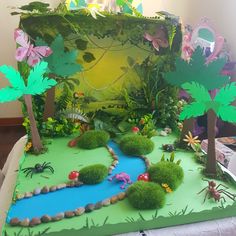 a cake made to look like a jungle scene with animals and plants on the grass