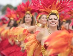 a group of women in red and yellow costumes with feathers on their head, smiling at the camera