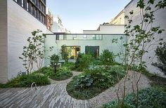 an outdoor courtyard with wooden walkways and lots of greenery on the sides of buildings