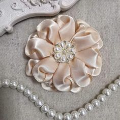 a close up of a flower on a pillow with pearls and beads next to it