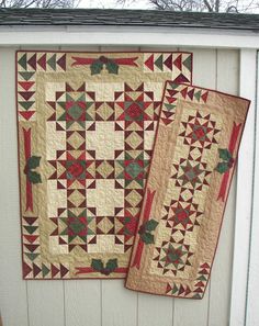 two quilts hanging on the side of a white building with red and green accents