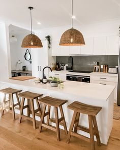 a kitchen island with stools in front of it and lights hanging from the ceiling