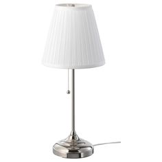 a lamp with a white shade on the base and a cord plugged into it