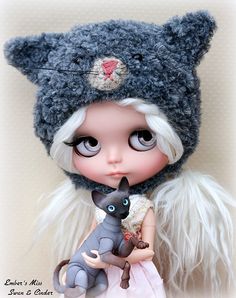 a close up of a doll with a cat on it's shoulder and an animal in her hand