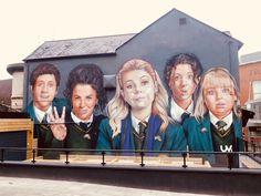 a large mural on the side of a building with people in school uniforms painted on it