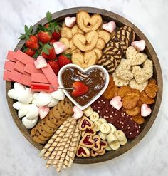 a heart shaped bowl filled with assorted snacks