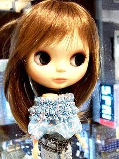 a close up of a doll with brown hair and blue dress in front of a store window