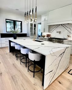 a large kitchen with marble counter tops and bar stools in the middle of it