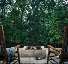 two wooden chairs sitting in front of an outdoor fire pit