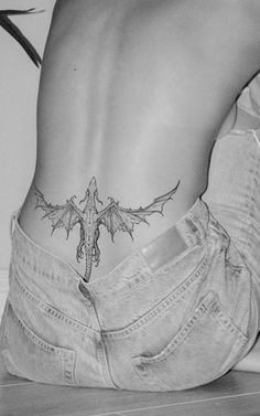 a woman's back with a tattoo on her lower body and the bottom part of her stomach