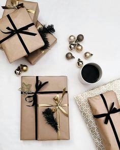 two wrapped presents sitting next to each other on top of a white table with gold and black decorations