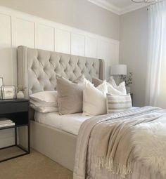 a bed with white linens and pillows in a bedroom next to a chandelier