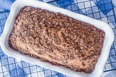 a cake in a white dish on a blue and white checkered table cloth