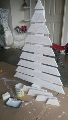 a wooden christmas tree sitting on top of a table next to a paint can and brush