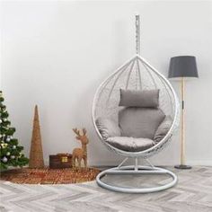 a white hanging chair next to a christmas tree