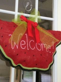 a welcome sign hanging from the side of a door with watermelon on it