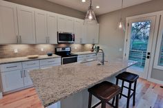 a kitchen with white cabinets and granite counter tops