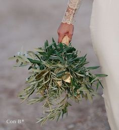 a bride holding a bouquet of greenery in her hand