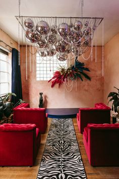 a living room filled with red couches and lots of chandelier hanging from the ceiling