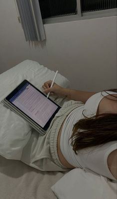 a woman is laying in bed with her laptop on her lap and writing on the screen