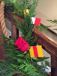 a red rose sitting on top of a green plant next to a wooden banister